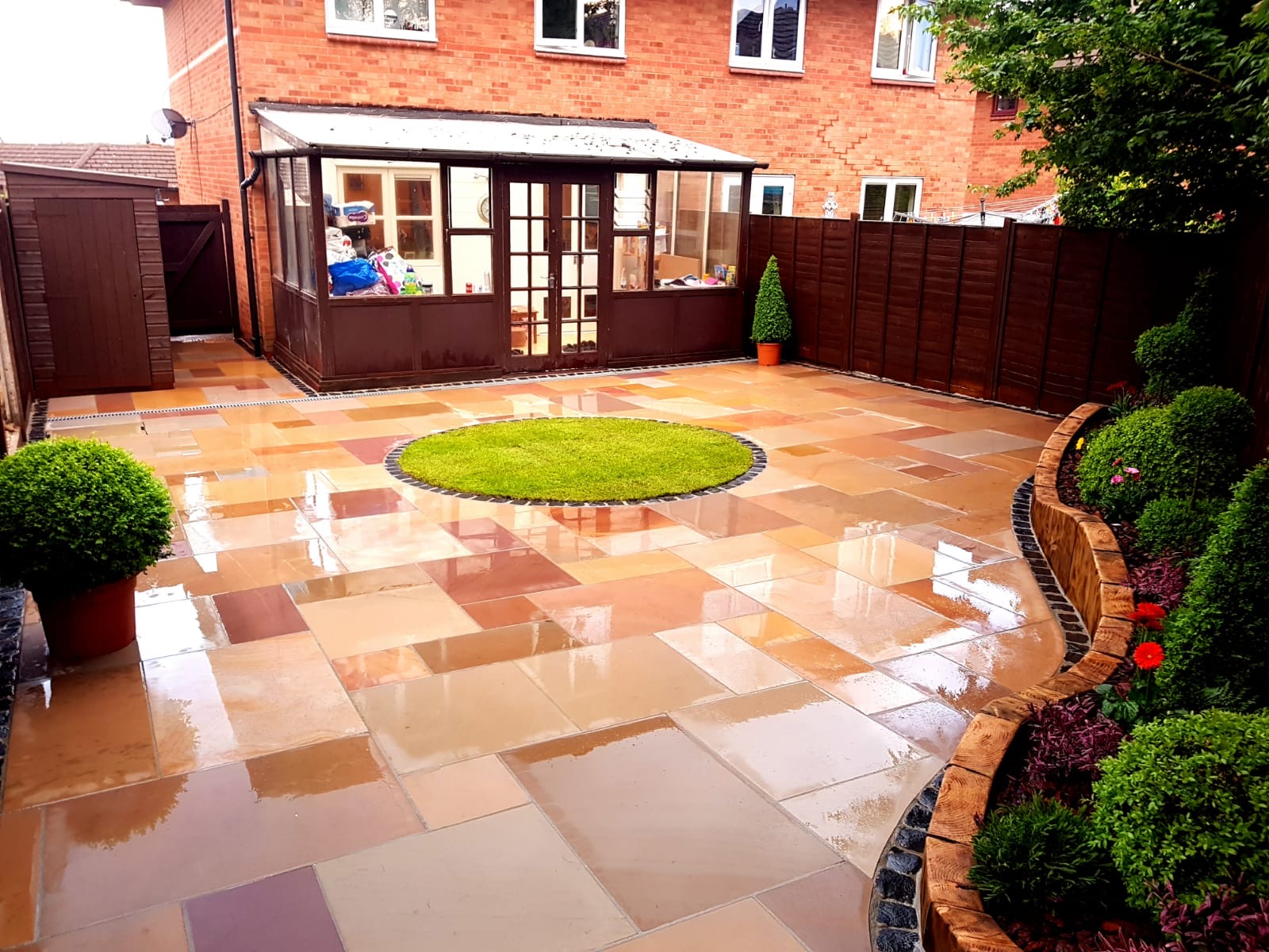 Residential garden with multi-colored porcelain paving and circular lawn